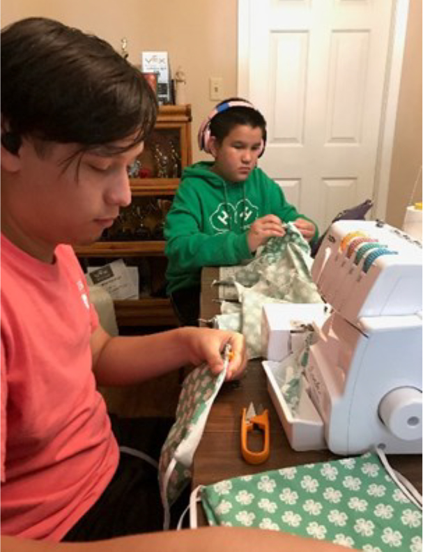 Tow Madison County 4-H'ers cutting and sewing material for COVID 19 masks