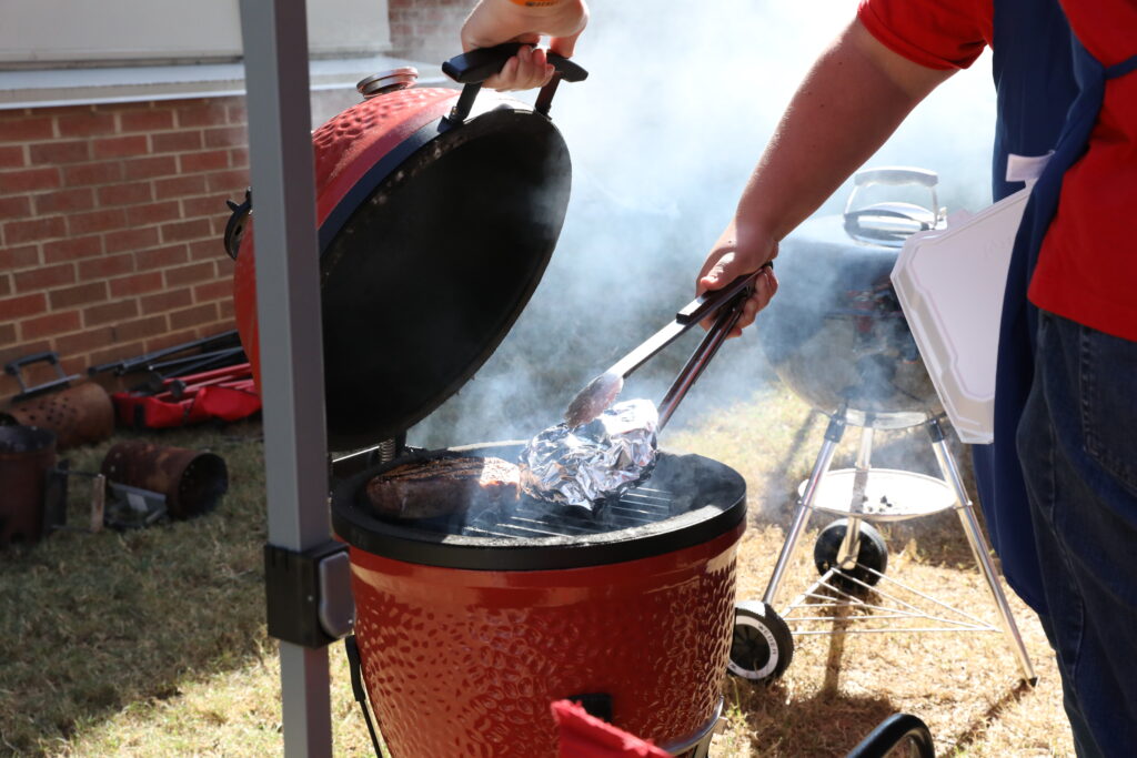 up-close photo of an egg style grill as a 4-H'er is checking the cooking process.