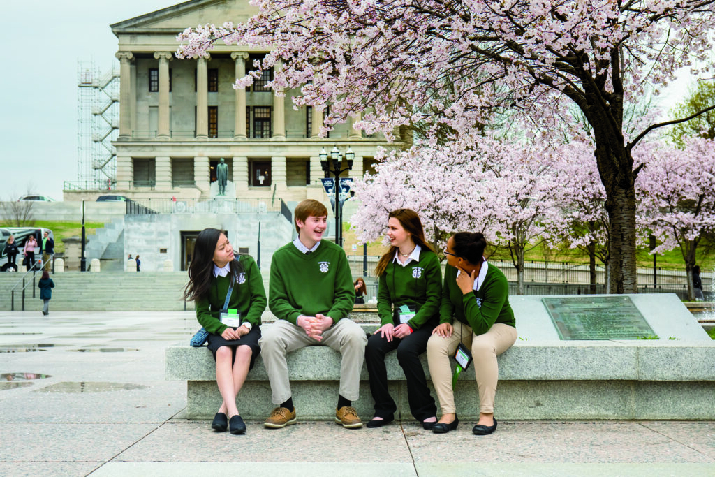 4-H congress youth sitting on a bench laughing in front of the TN capitol.